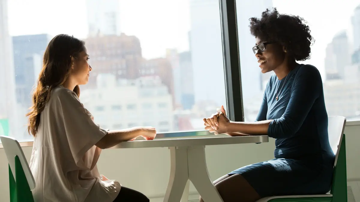 Two women sitting beside table and talking.