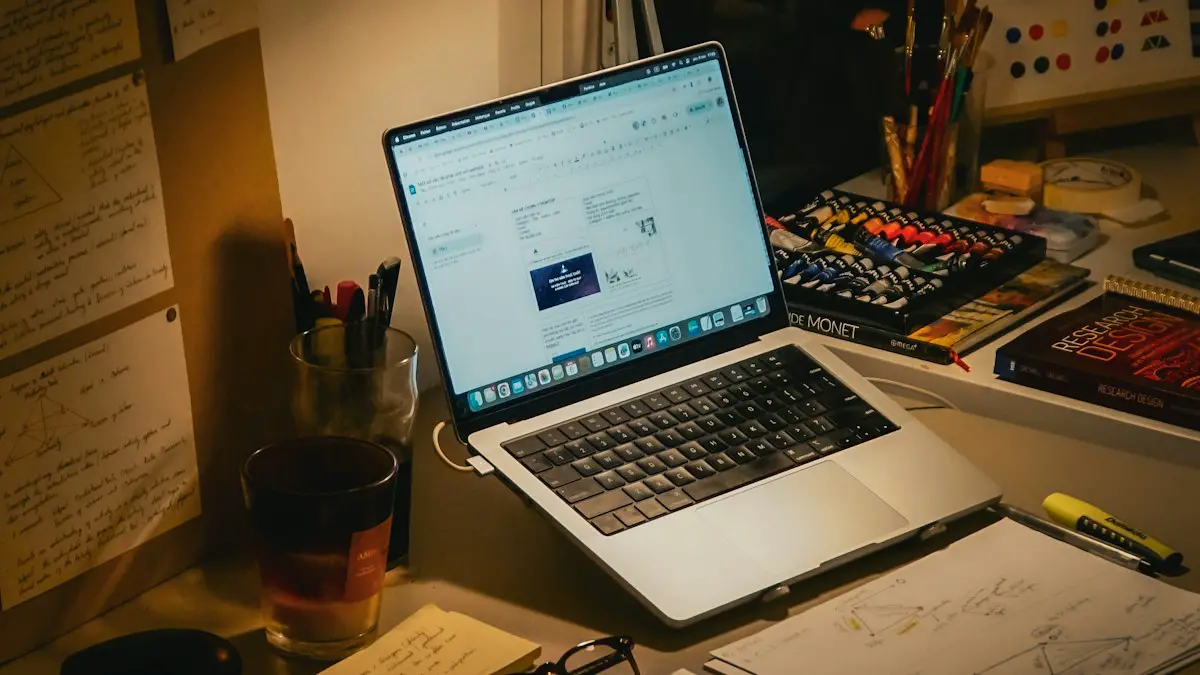 Desk with laptop, books, and papers at night.