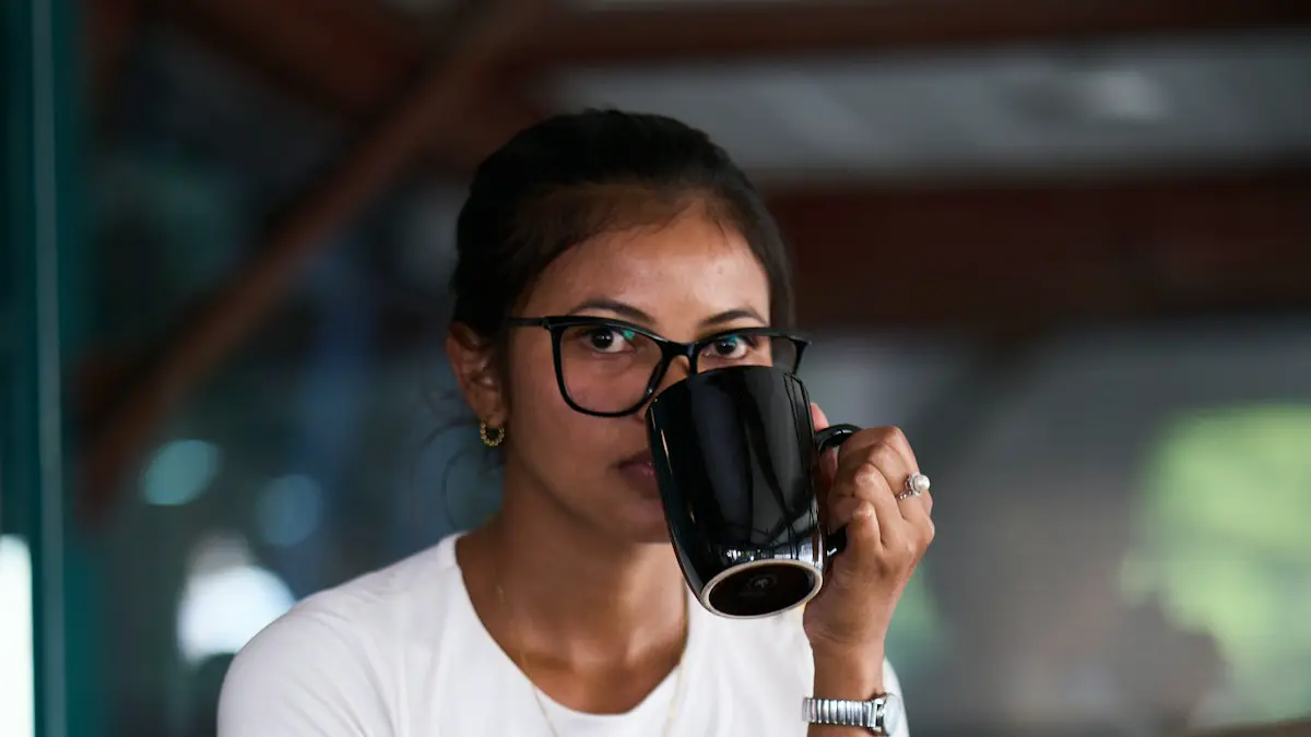 Woman sips coffee while working on a laptop.