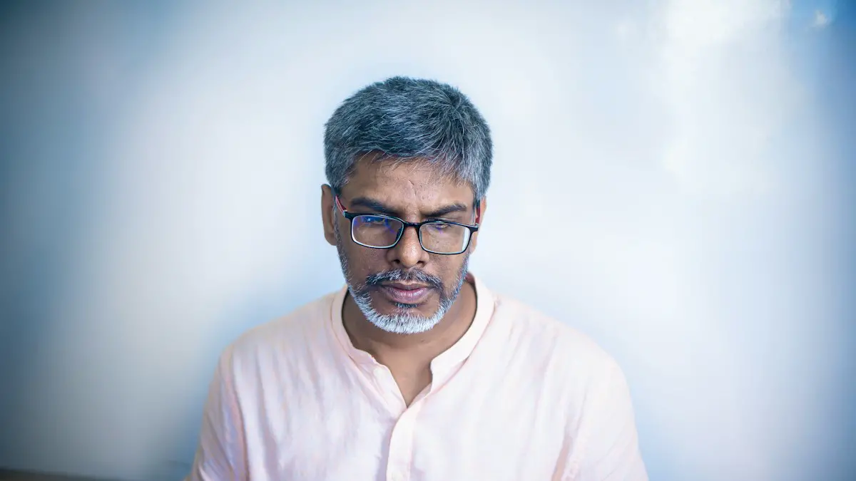 Man wearing glasses looking down at laptop.