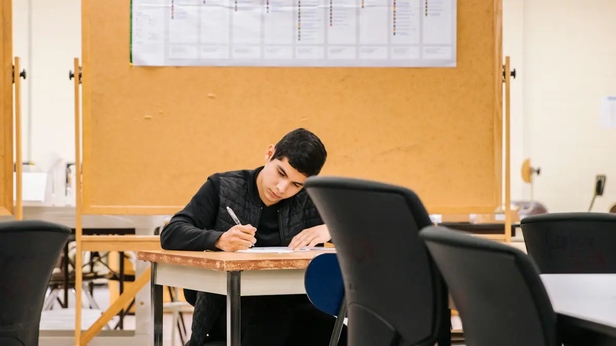 A student writing answers alone at a desk in a quiet exam hall.