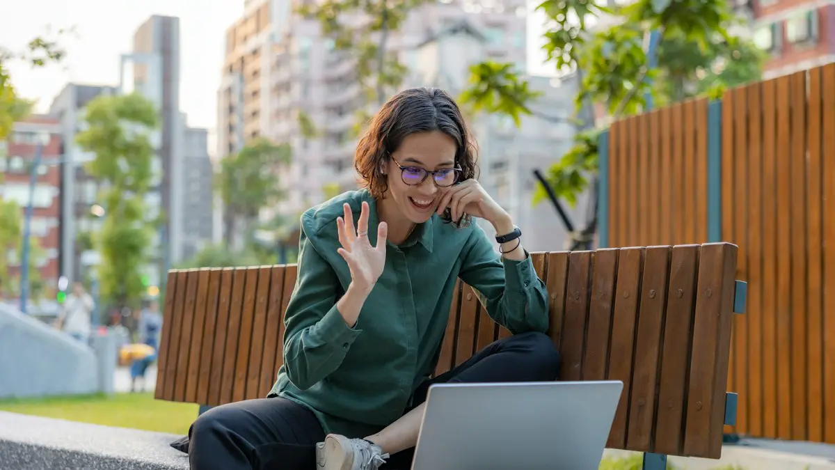 A woman sitting on a bench with a laptop.