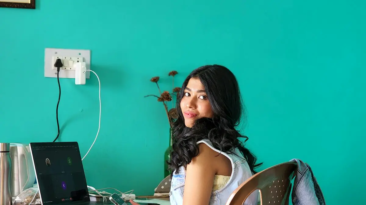 A woman sitting on a bed with a laptop.
