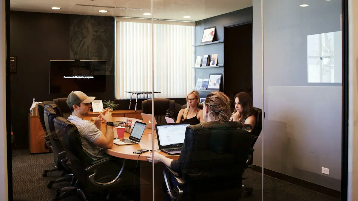 People sitting near table with laptop computer.