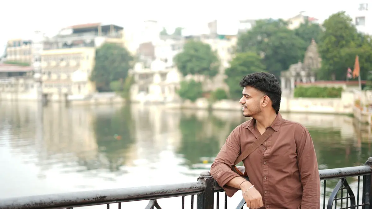 Young man looking out over a lake with buildings.