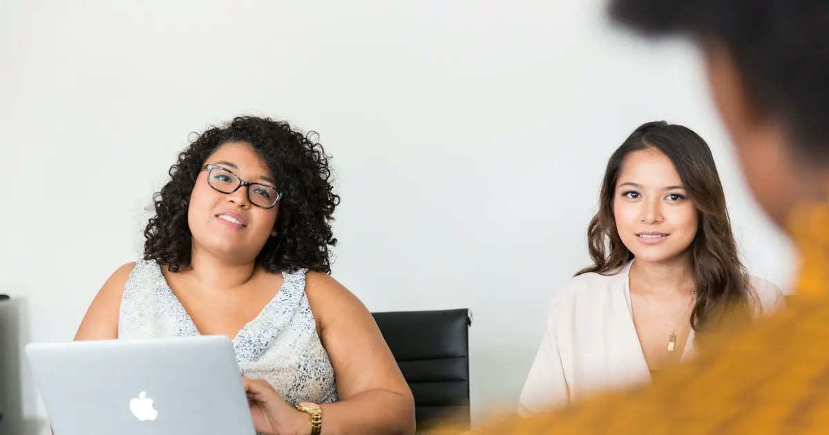 An HR interviewer talking with a candidate at a laptop.
