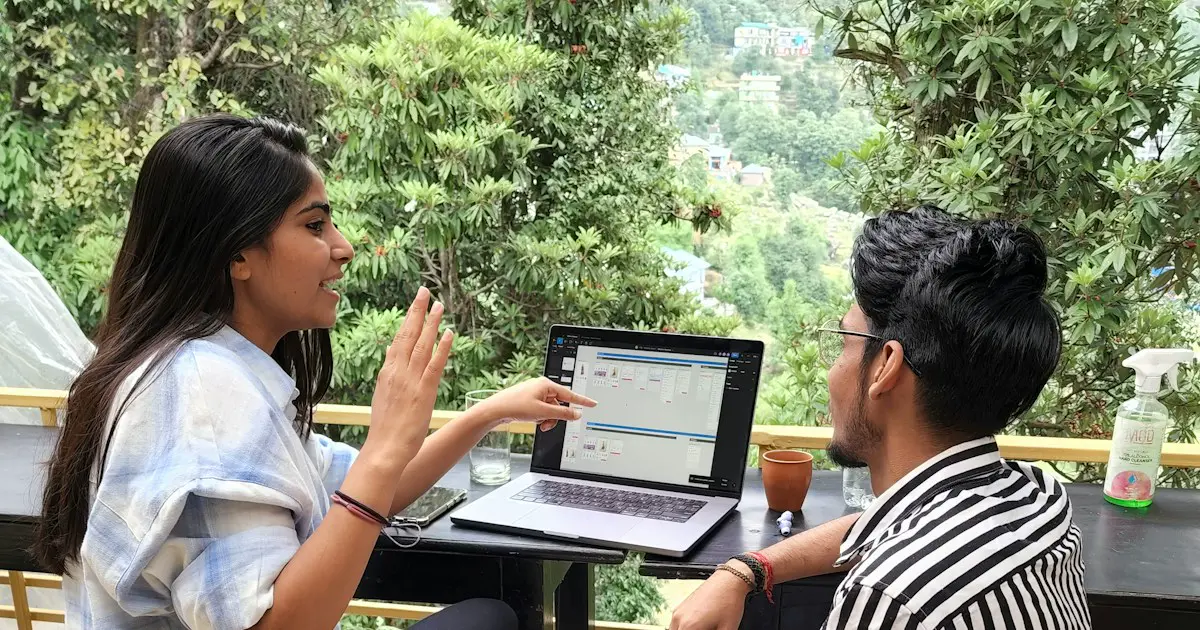 Two students discussing ideas over a laptop.