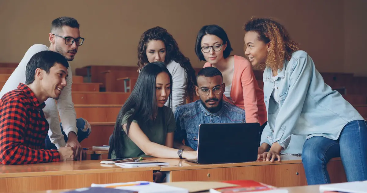 Students working together on a laptop in a lecture hall.