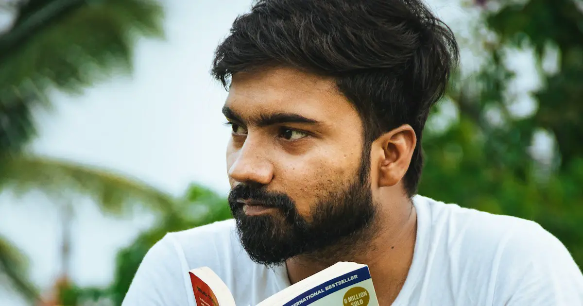 A young man reading a book outdoors.