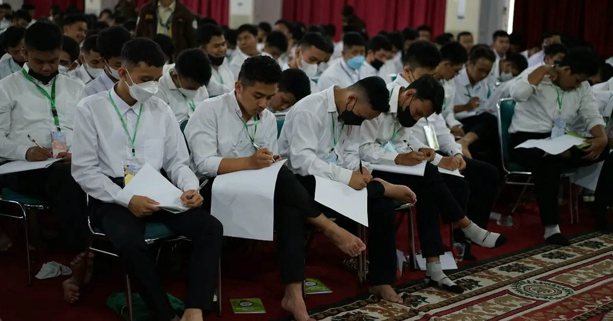 Students writing an exam in a large hall.