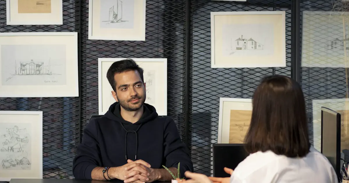 An interviewer talking with a candidate across a desk.