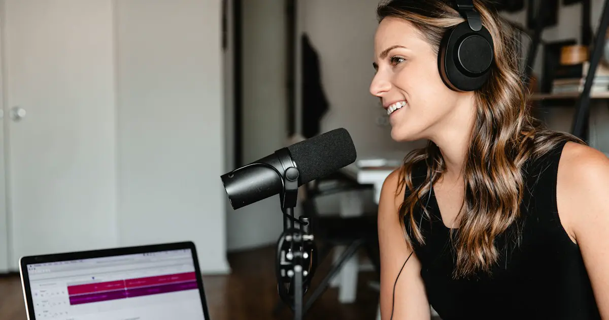 A woman recording herself speaking at a microphone.