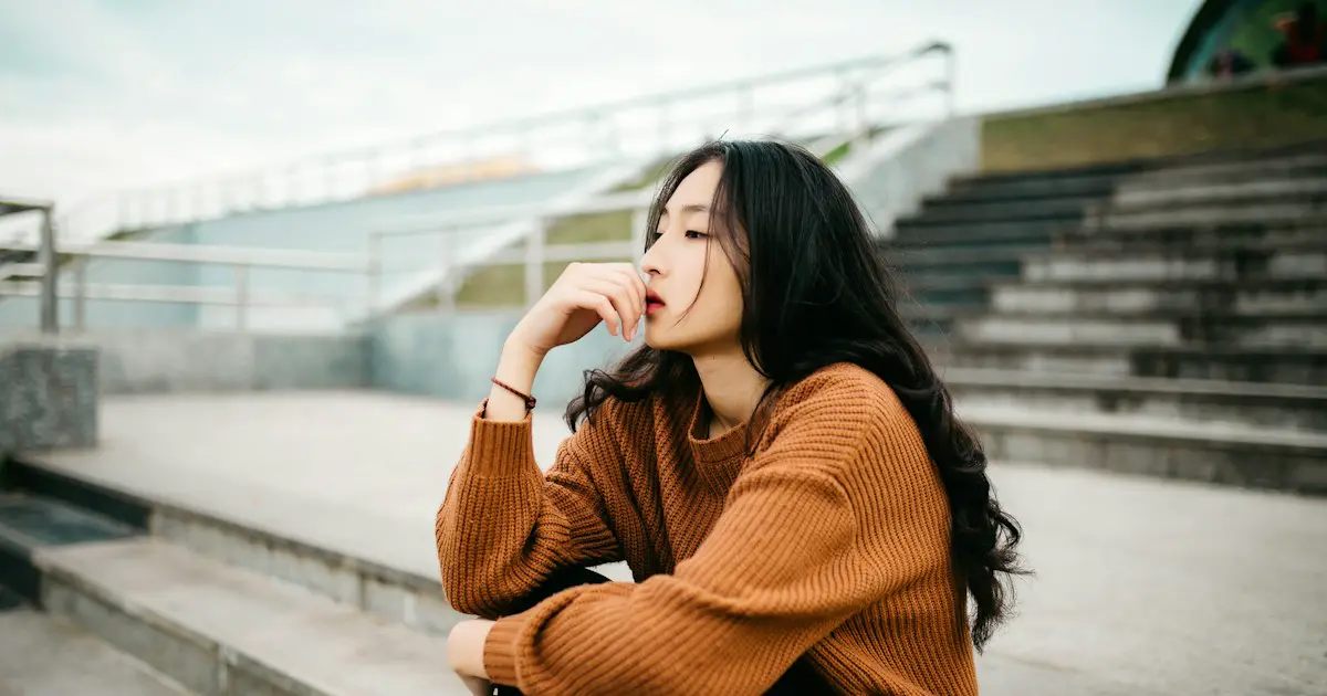 A young woman pausing to think on some steps.