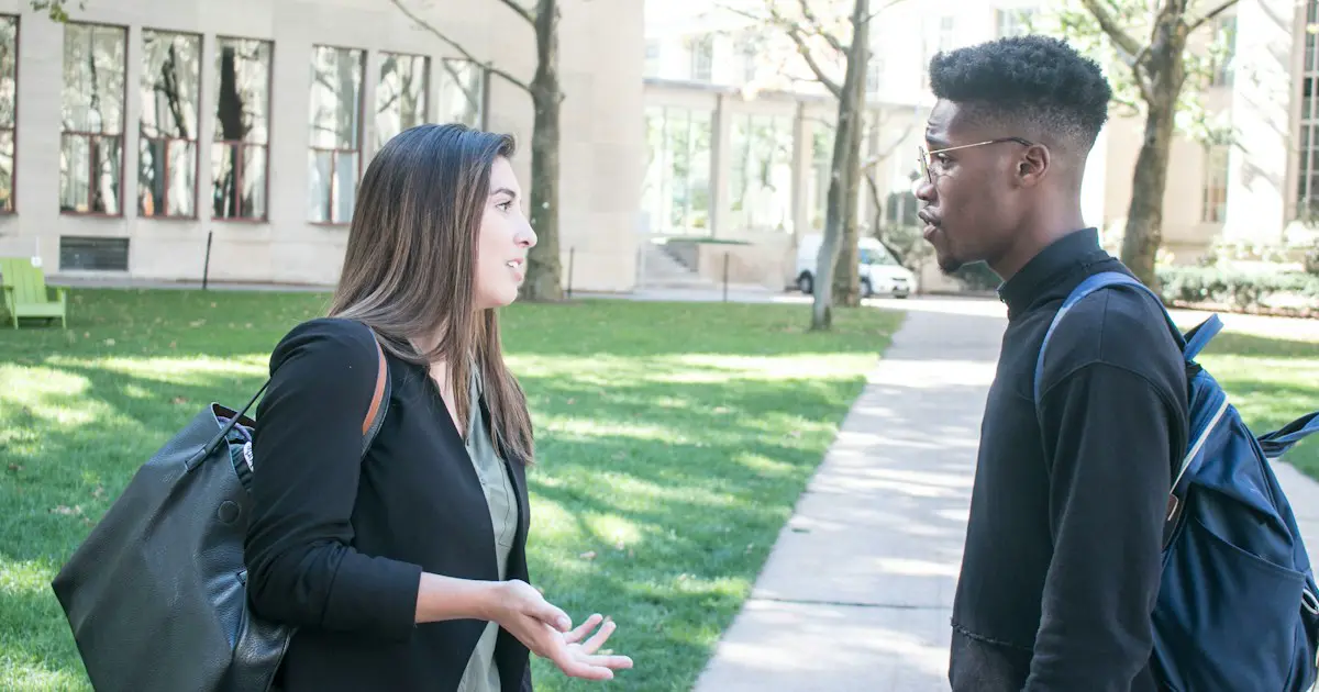 Two students talking as they walk across campus.
