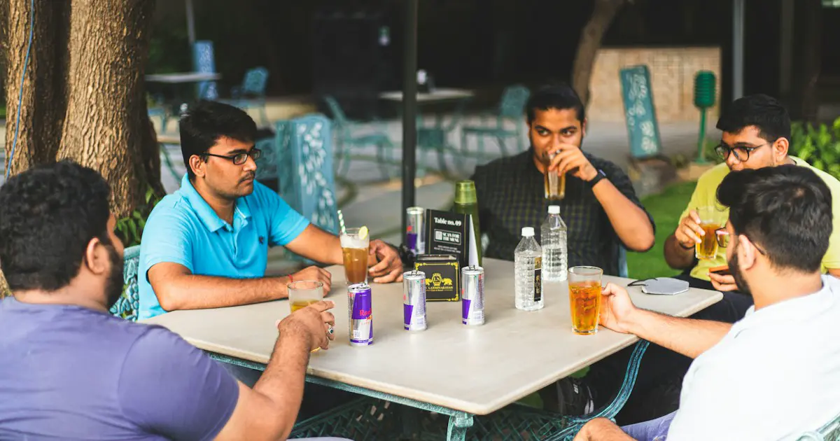 Friends talking over drinks at a cafe table.