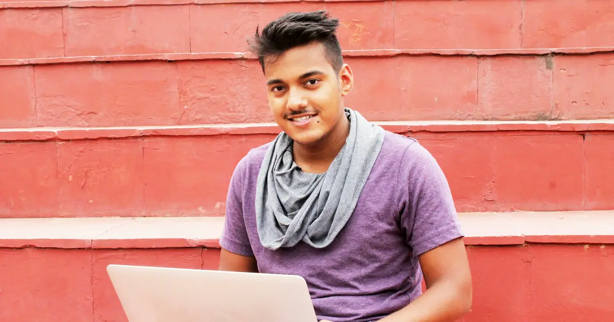 A student practising on a laptop on college steps.