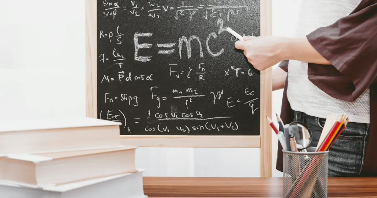 Physics equations on a chalkboard behind a pile of books.