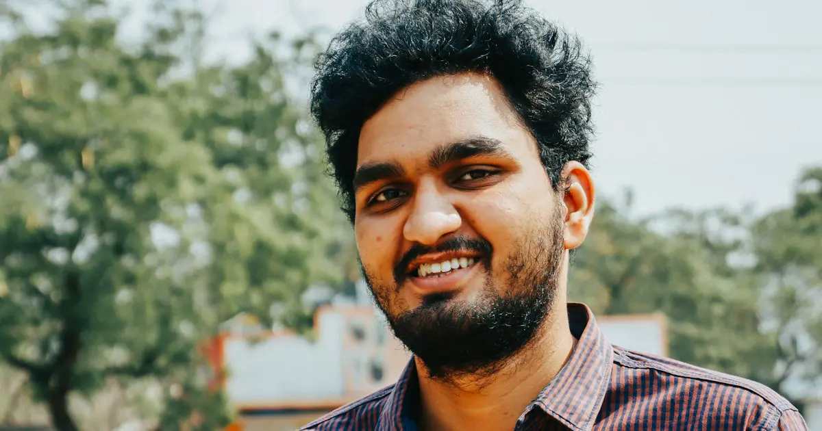 A young man smiling confidently.
